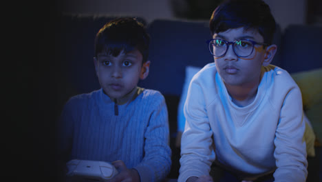 Front-View-Of-Two-Young-Boys-At-Home-Having-Fun-Playing-With-Computer-Games-Console-On-TV-Holding-Controllers-Late-At-Night-5